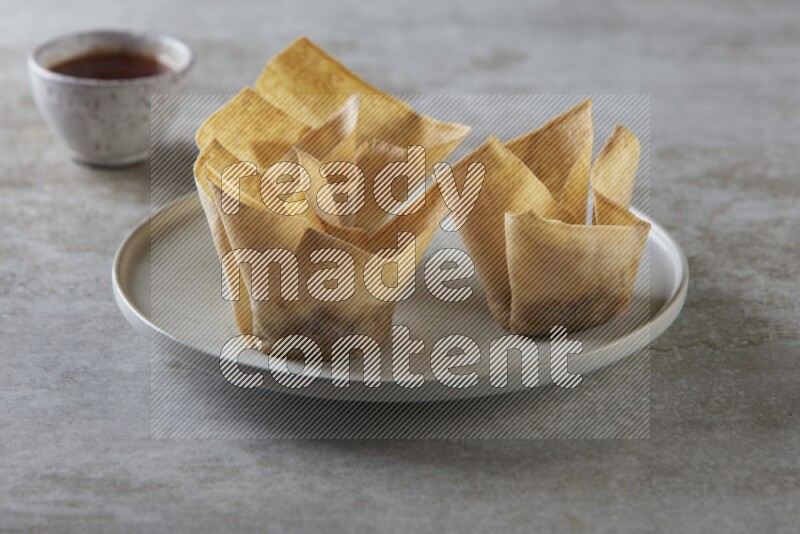wonton cups with soy sauce ramkin on grey ceramic plate on grey textured counter top