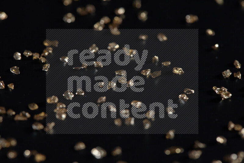 قطع زجاجية ذهبية لامعة متناثرة على خلفية سوداء