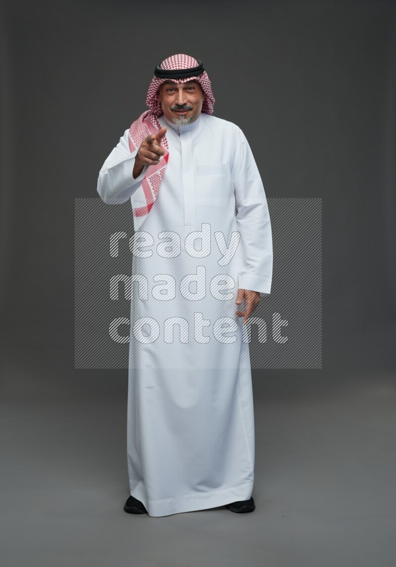 Saudi man with shomag Standing Interacting with the camera on gray background