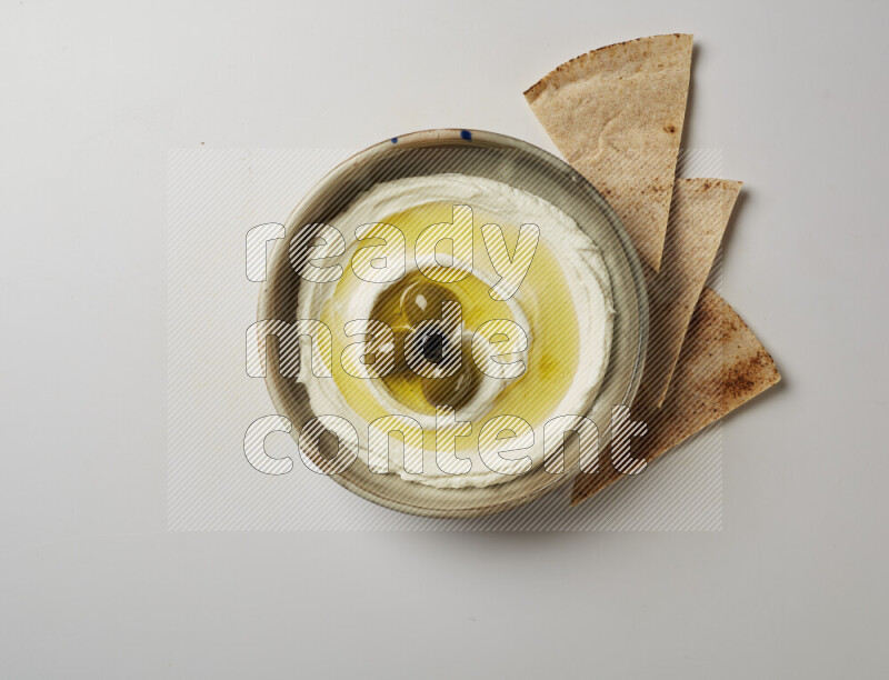 Lebnah garnished with whole olives in a grey pottery plate on a white background