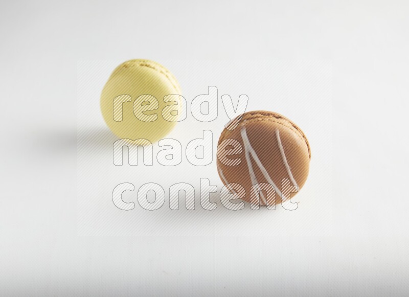 45º Shot of of two assorted Brown Irish Cream, and Yellow Lime macarons on white background