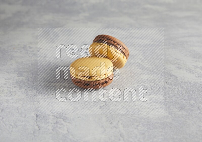 45º Shot of two Yellow and Brown Chai Latte macarons r on white  marble background