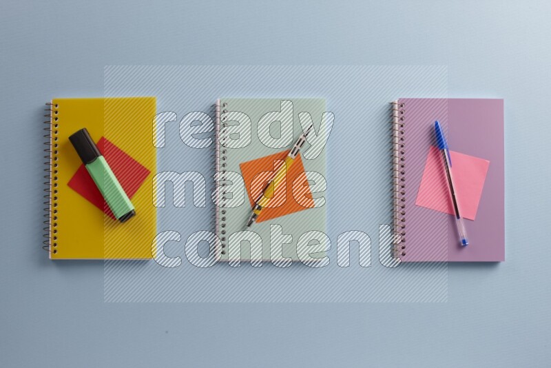 Multicolored notebooks with different school supplies on blue background