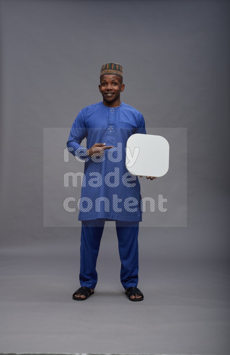 Man wearing Nigerian outfit standing holding social media sign on gray background