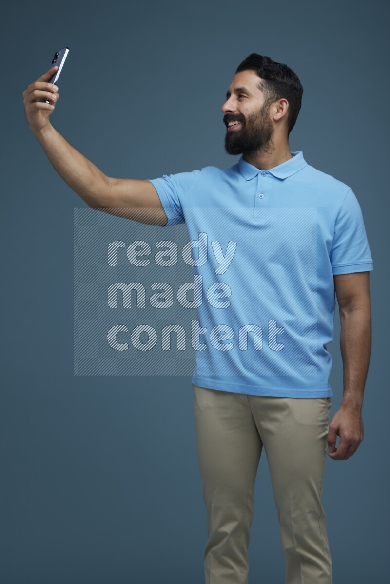 Man Taking a Selfie in a blue background wearing a Blue shirt