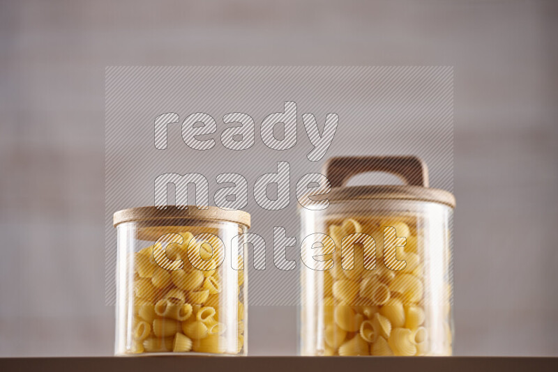 Raw pasta in glass jars on beige background