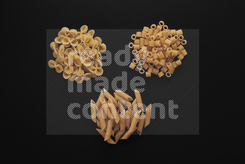 Different pasta types in bunches on black background