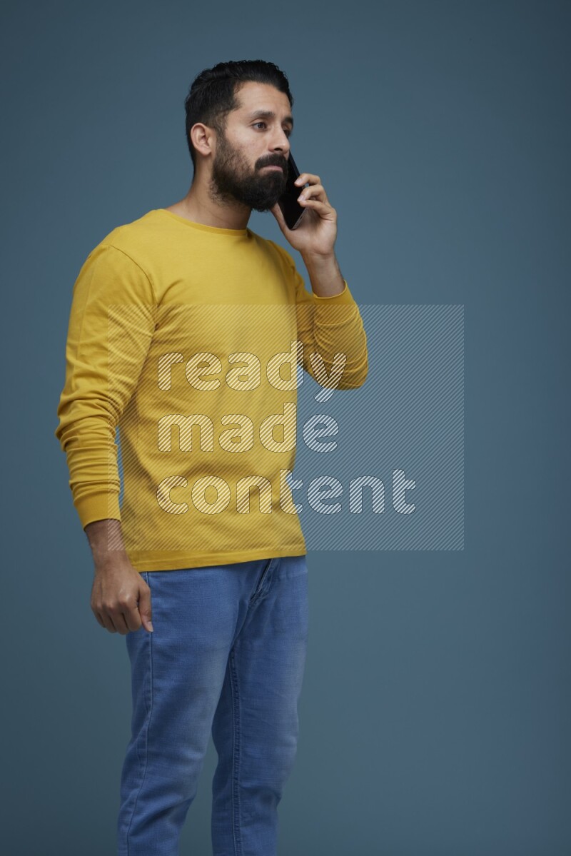 A man having a calling in a blue background wearing a yellow shirt