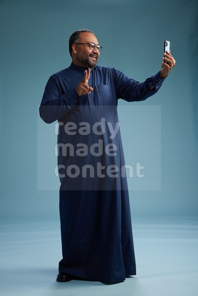 Saudi Man without shimag Standing taking selfie on blue background