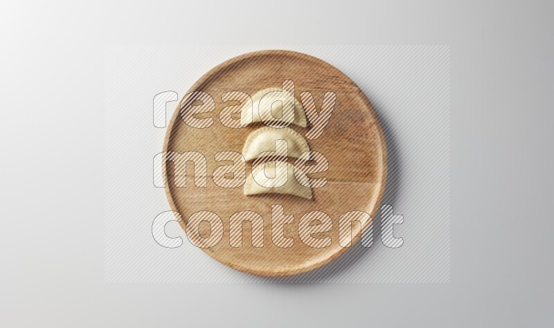 Three Sambosas on a wooden round plate on a white background