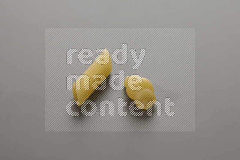 Penne pasta with other types of pasta on grey background