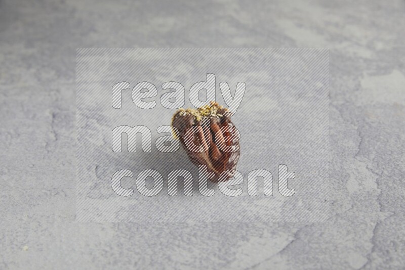 pecan stuffed date covered with Dark chocolate and chopped pistachios on alight grey background