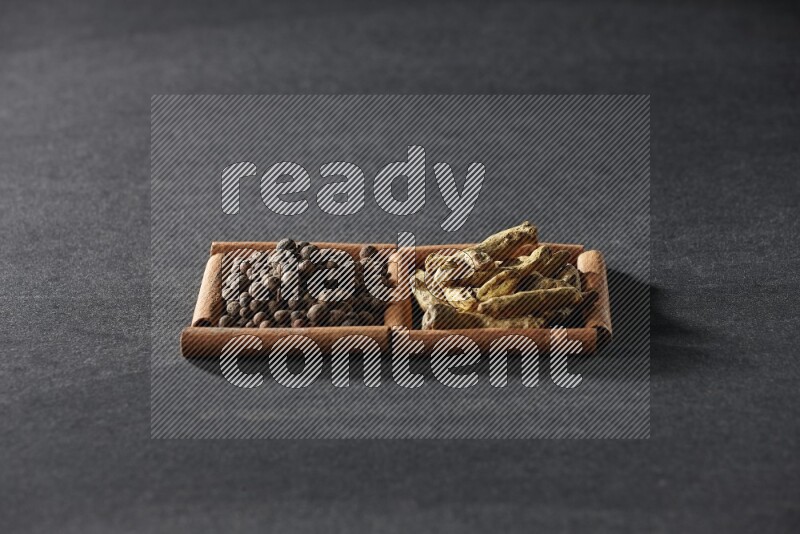 2 squares of cinnamon sticks full of allspice and turmeric fingers on black flooring