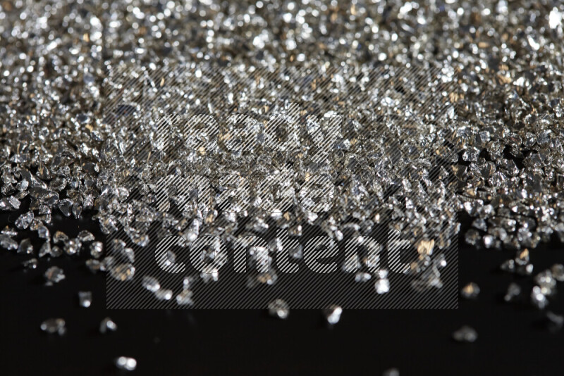 Silver shimmering fragments of glass scattered on a black background