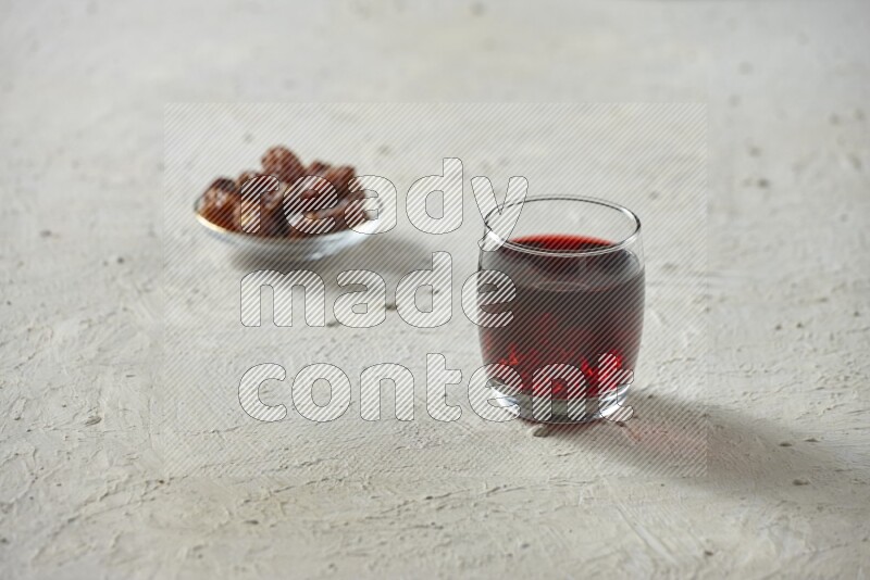Cold drinks in a glass cup with dates such as water, tamarind, qamar eldin, sobia, milk and hibiscus on textured white background