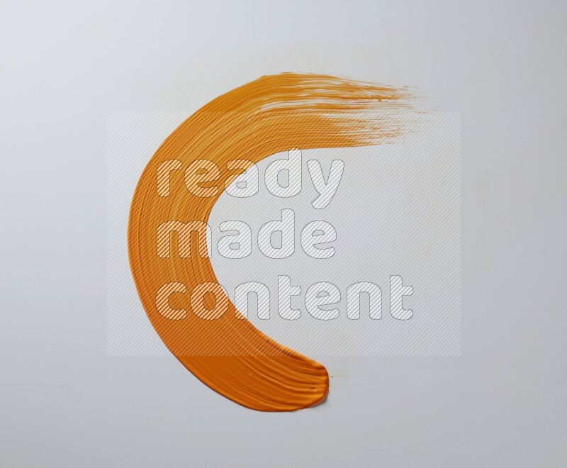 An orange half circular painting brush stroke on white background