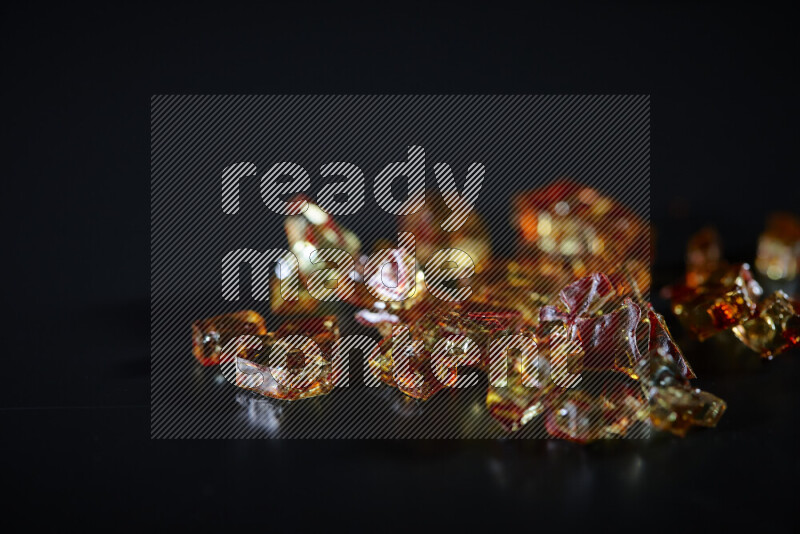 Transparent orange fragments of glass scattered on a black background