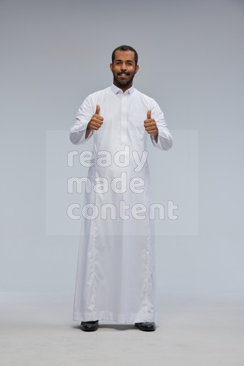 Saudi man Wearing Thob standing interacting with the camera on Gray background