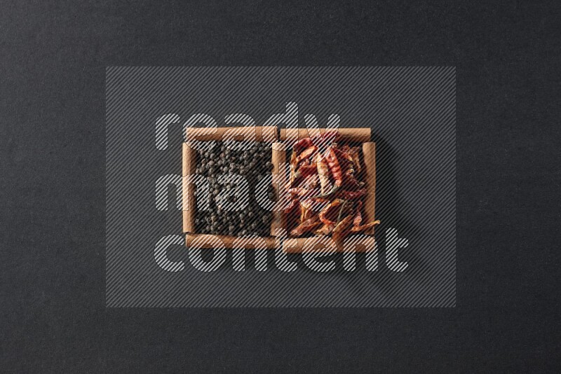 2 squares of cinnamon sticks full of chilis and black peppers on black flooring