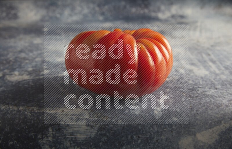 45 degree single heirloom tomato on a textured rustic blue background