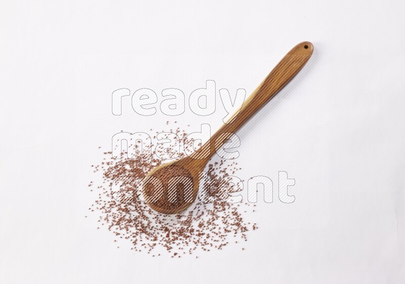 A wooden ladle full of garden cress seeds on a white flooring