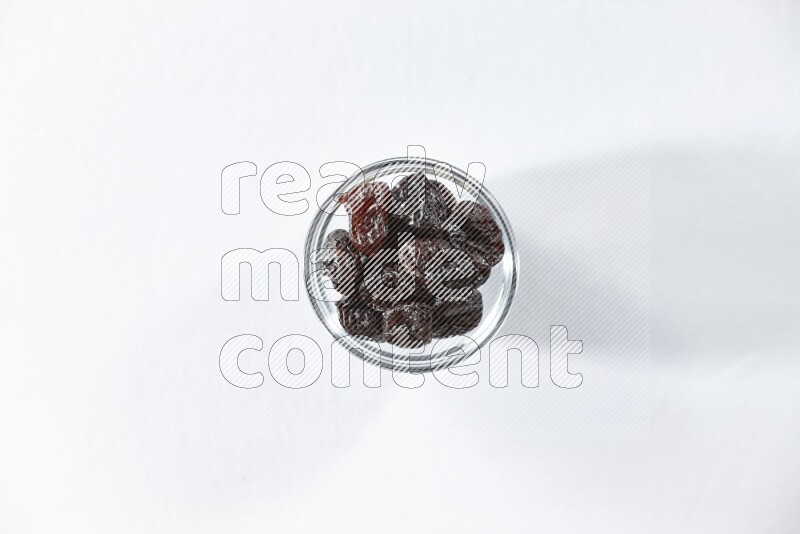 A glass bowl full of dried plums on a white background in different angles