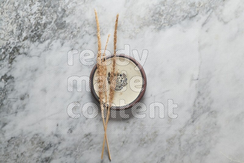 Wheat stalks on decorative pottery plate on grey marble background