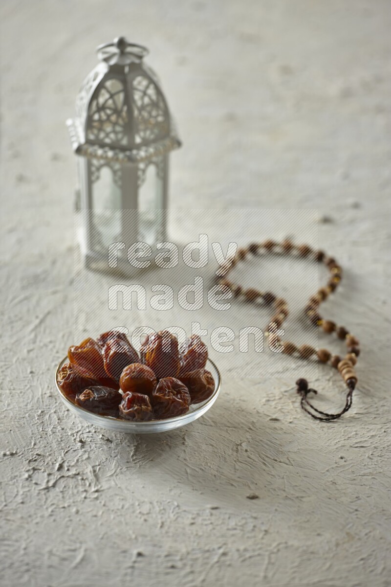 A white lantern with different drinks, dates, nuts, prayer beads and quran on white background