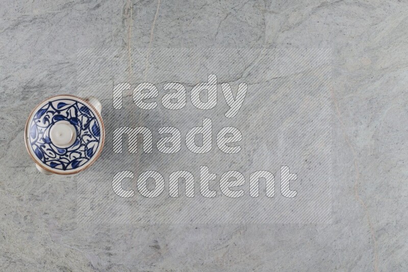 إناء فخاري متعدد الألوان مع غطائه على خلفية من الرخام الرمادي