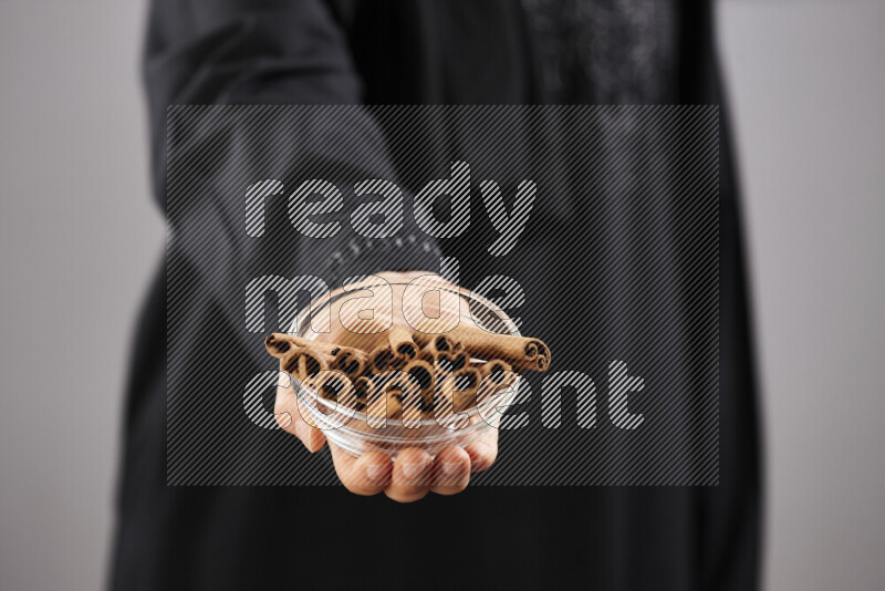 Woman in abaya holding different kinds of spices in different positions