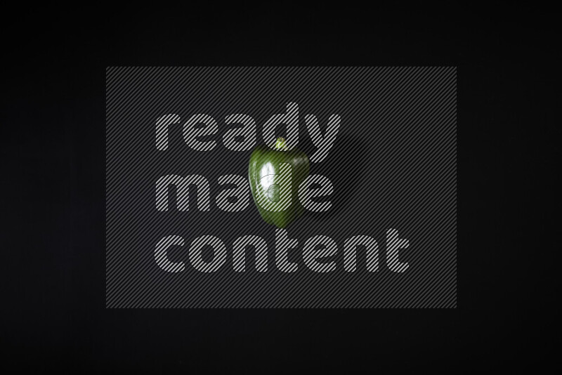 Green bell pepper on black background