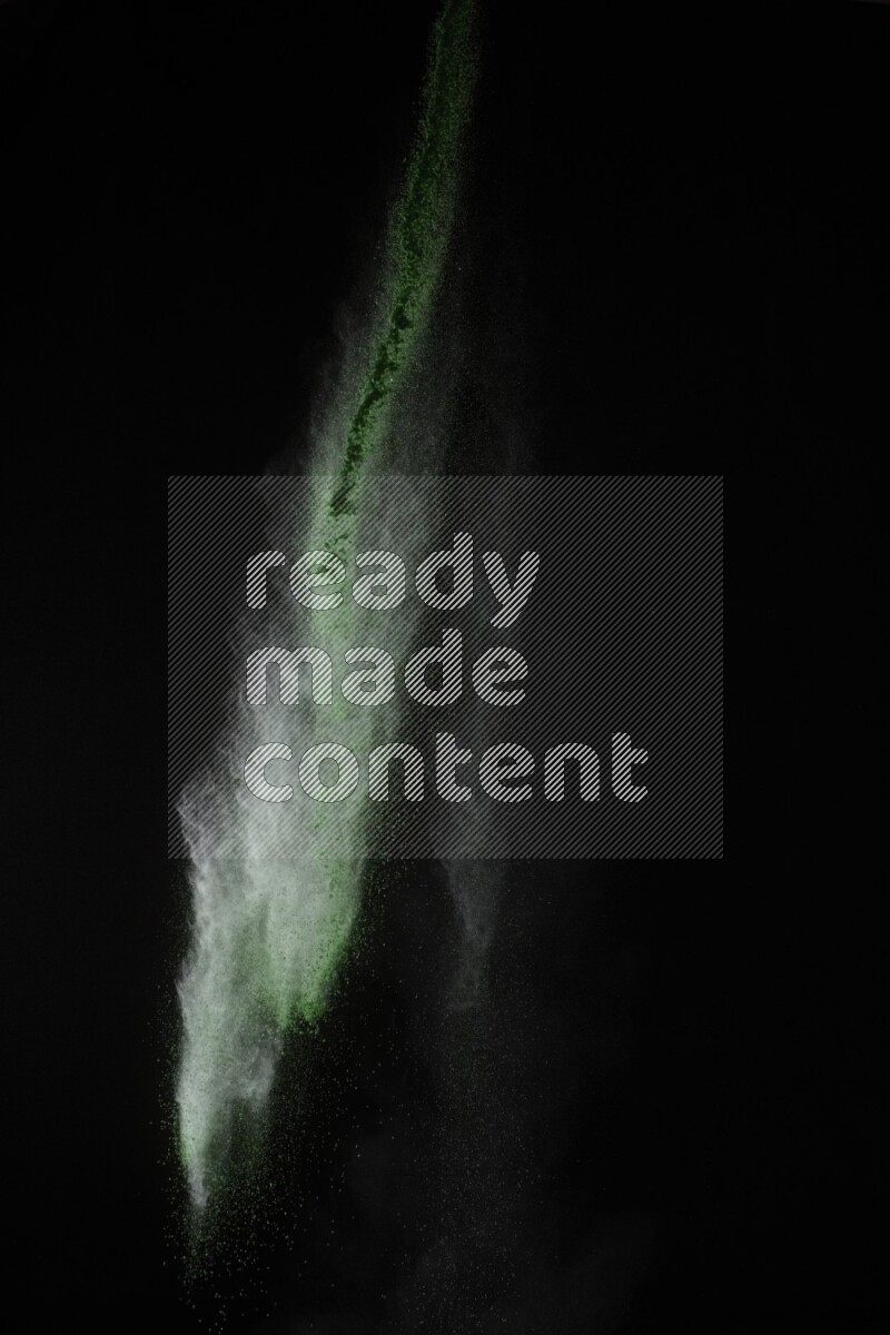 A side view of green powder explosion on black background