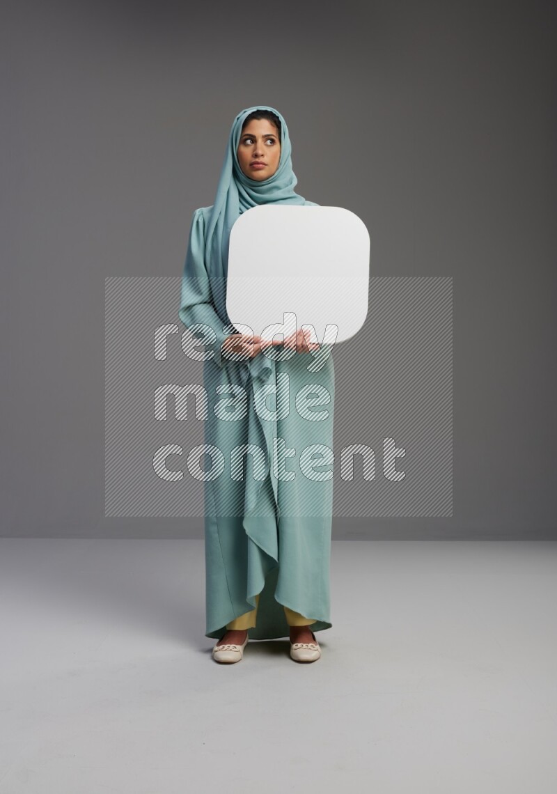 Saudi Woman wearing Abaya standing holding social media sign on Gray background