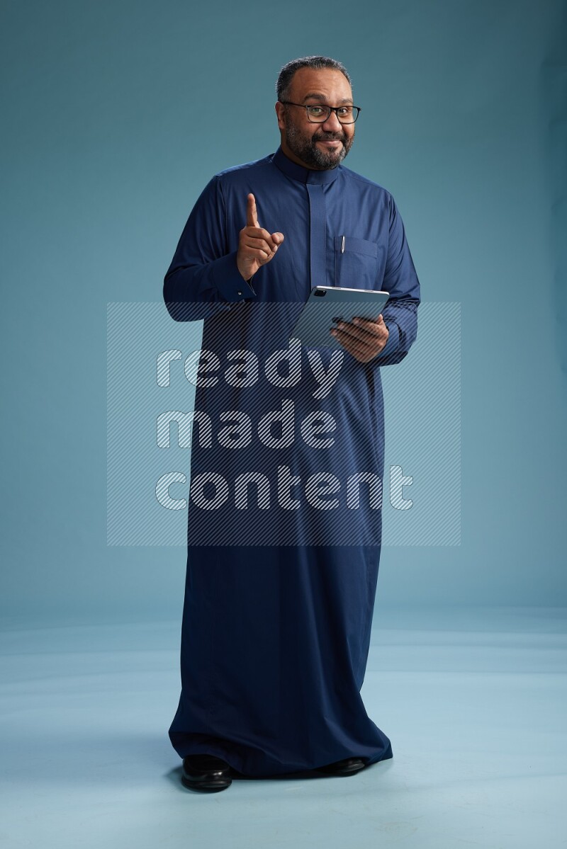Saudi Man without shimag Standing working on tablet on blue background