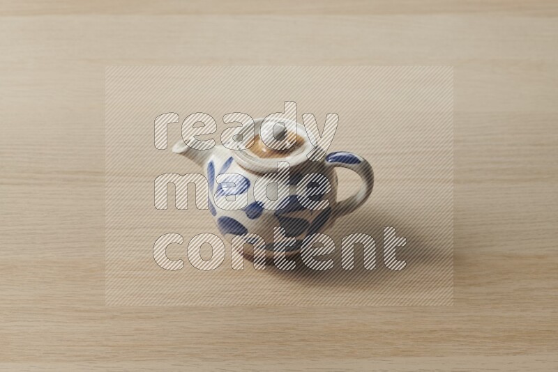 A pottery teapot on light wooden background