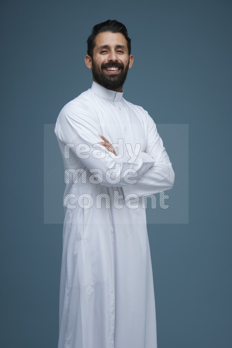 A man posing in a blue background wearing Saudi Thob