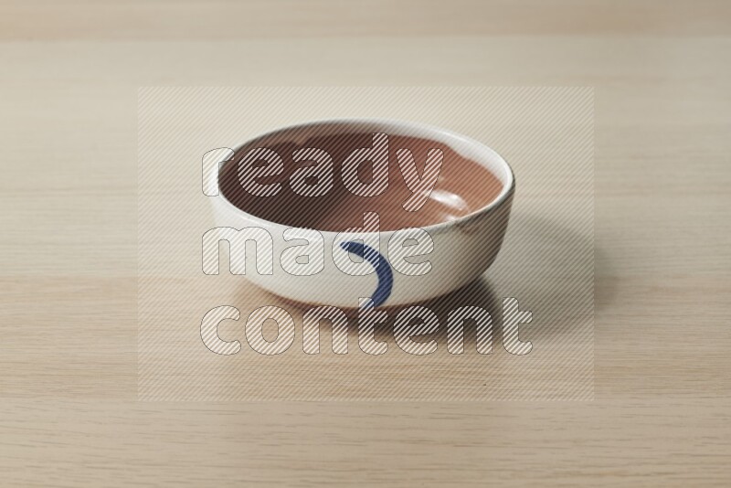 A multicolored pottery bowl on light wooden background