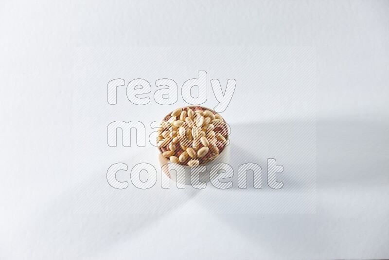 A beige ceramic bowl full of peeled peanuts on a white background in different angles