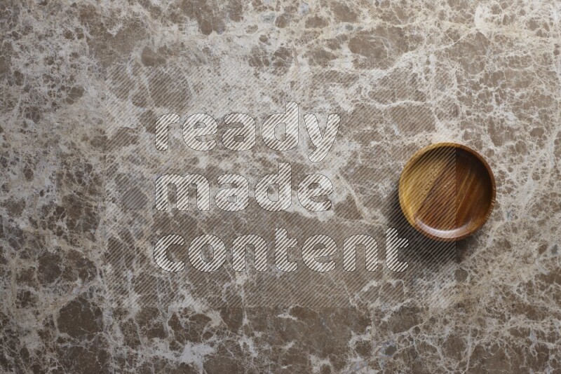 A wooden bowl on beige marble background