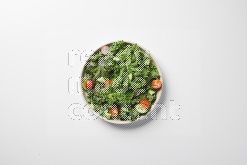 A bowl of fresh vegetables salad with kale leaves, cherry tomatoes, sliced radishes and sliced cucumber on a white background