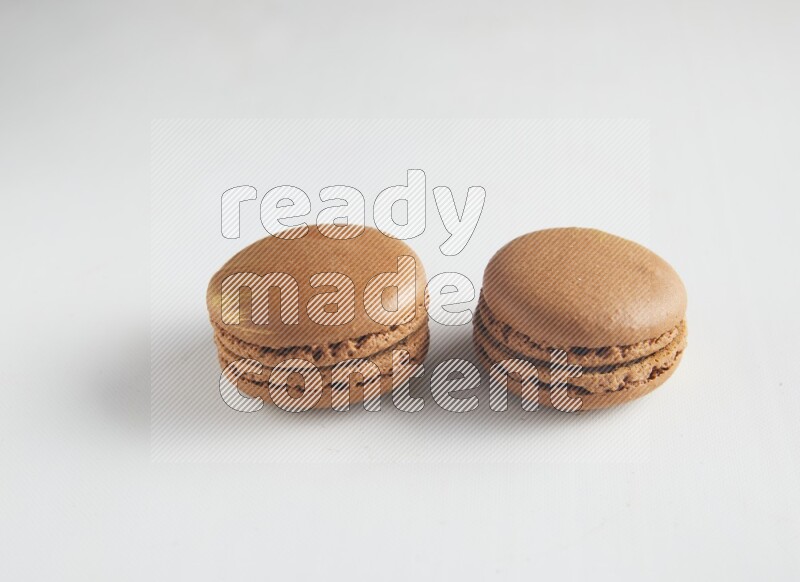 45º Shot of two Brown Coffee macarons on white background