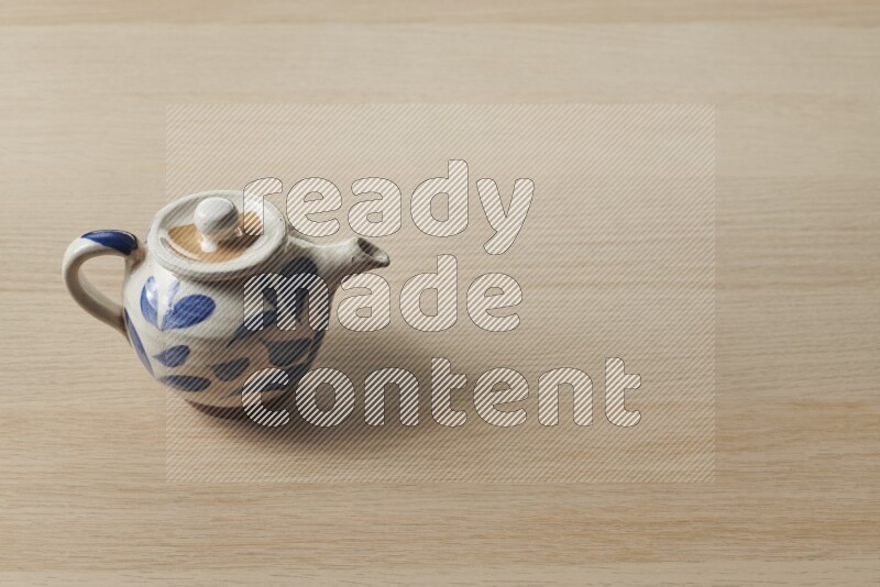 A pottery teapot on light wooden background
