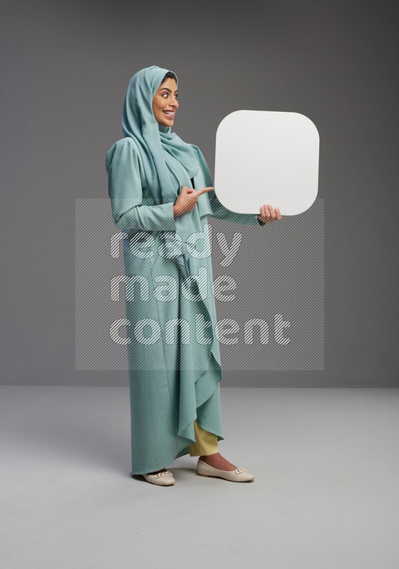Saudi Woman wearing Abaya standing holding social media sign on Gray background