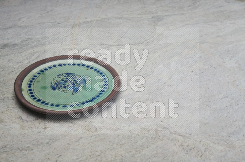 A decorative pottery plate on grey marble background