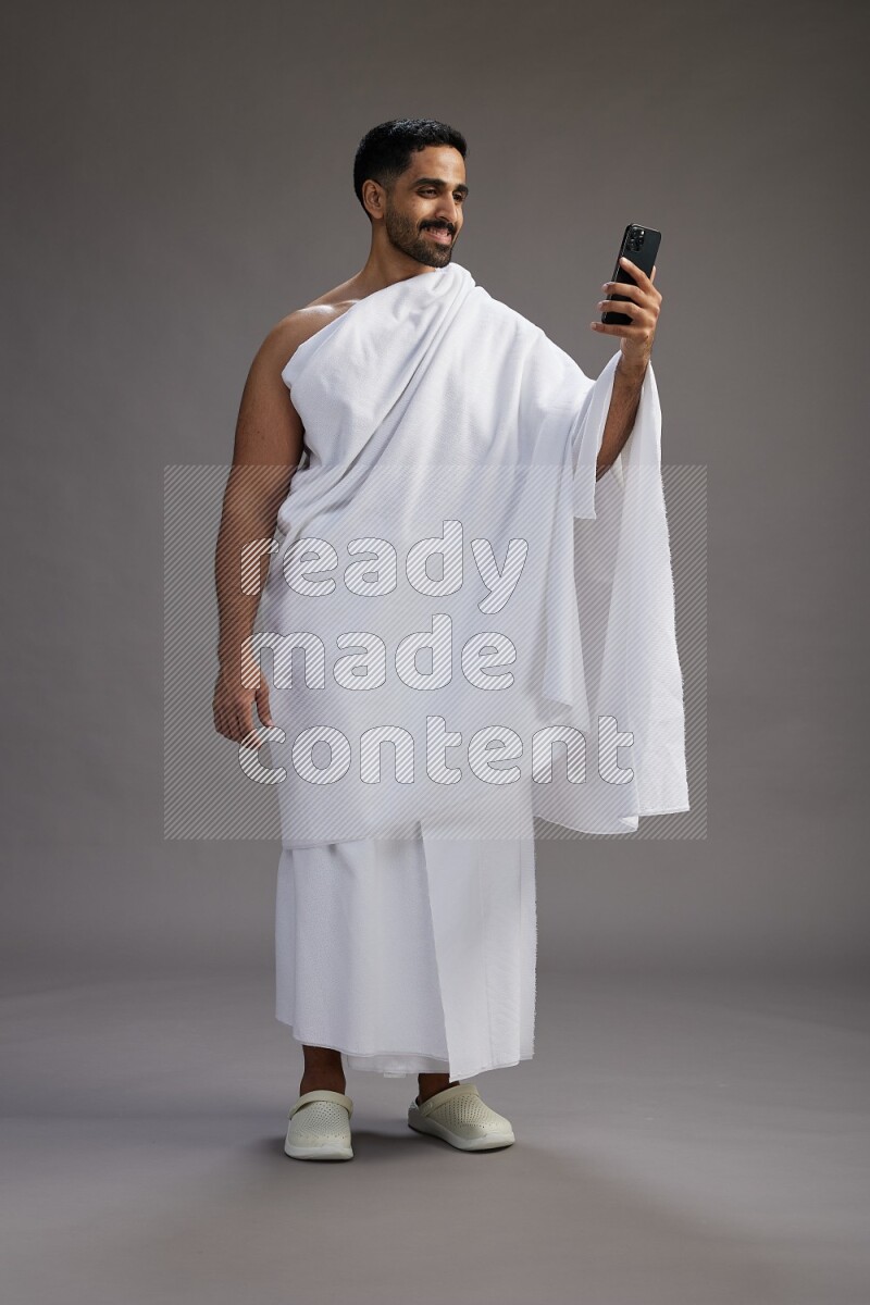 A man wearing Ehram Standing taking selfie on gray background