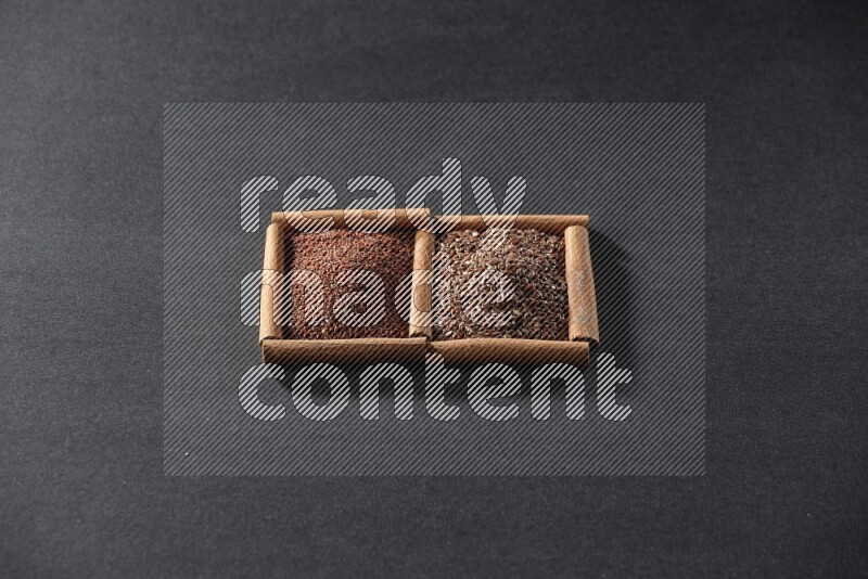 مربعان من أعواد القرفة ممتلئان بحب الرشاد وبذور الكتان علي خلفية سوداء