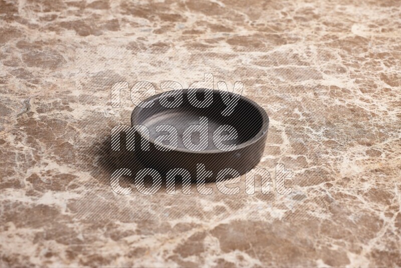 A black pottery bowl on beige marble background