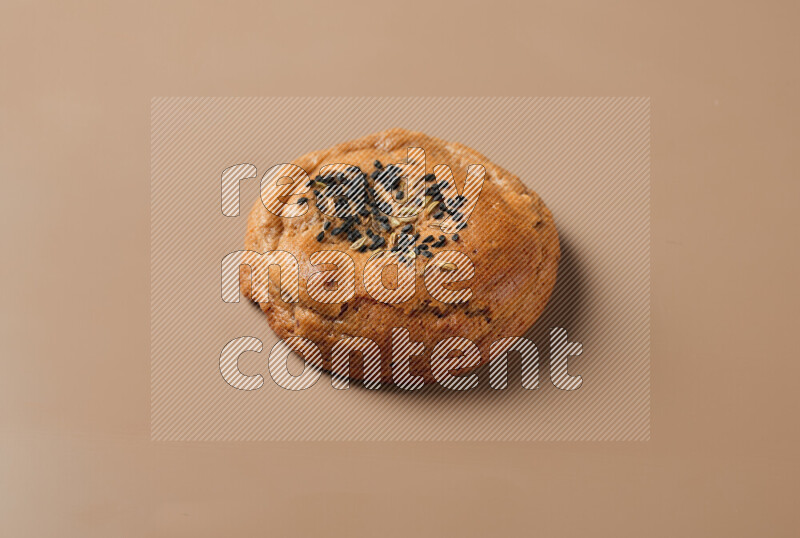 a whole Hasawi cookie with grains on a brown background