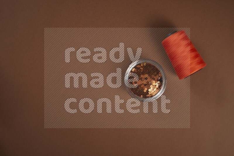 مجموعة من أدوات الخياطة والتفصيل برتقالية اللون على خلفية بنية