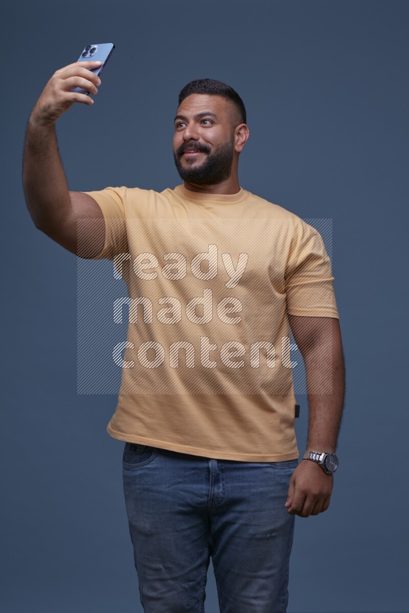 A man Taking A Selfie on Blue Background wearing Orange T-shirt